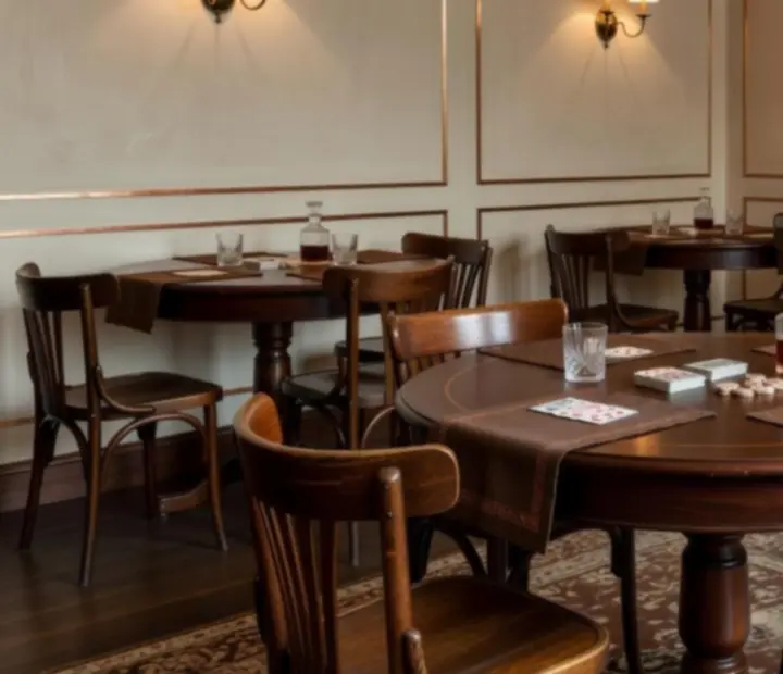 A softly lit private card room with wooden tables and upholstered chairs prepared for an evening gathering